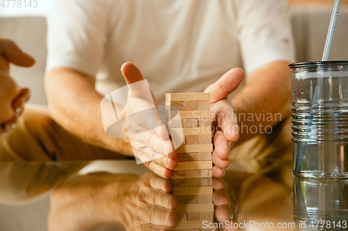 Image of Close up of senior man\'s hands doing his wooden constructor at home - concept of home studying