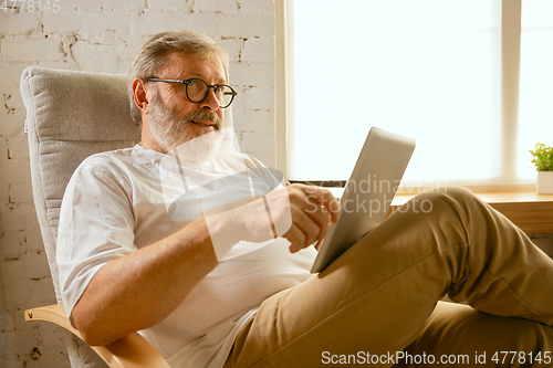 Image of Senior man working with tablet at home - concept of home studying