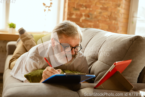 Image of Senior man working with tablet at home - concept of home studying