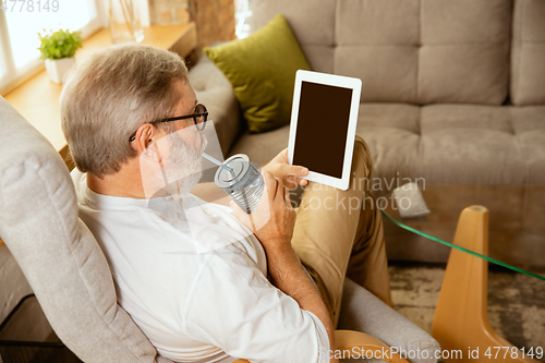 Image of Senior man working with tablet at home - concept of home studying