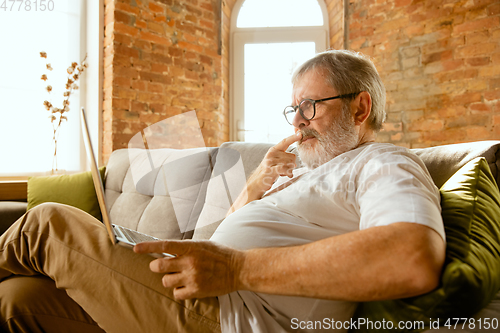 Image of Senior man working with laptop at home - concept of home studying