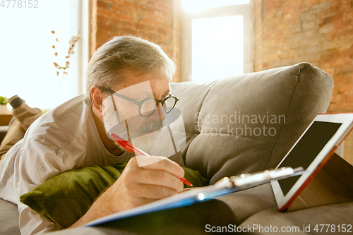 Image of Senior man working with tablet at home - concept of home studying