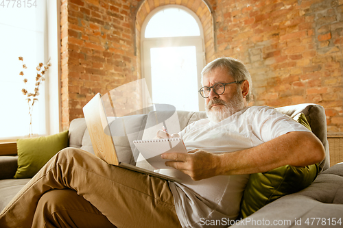 Image of Senior man working with laptop at home - concept of home studying