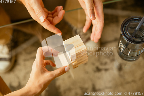 Image of Close up of senior man\'s hands doing his wooden constructor at home - concept of home studying