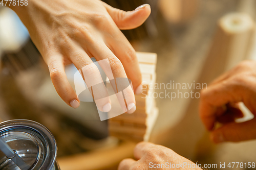 Image of Close up of senior man\'s hands doing his wooden constructor at home - concept of home studying