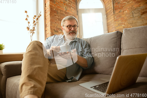 Image of Senior man working with laptop at home - concept of home studying