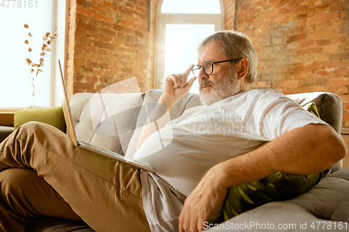 Image of Senior man working with laptop at home - concept of home studying