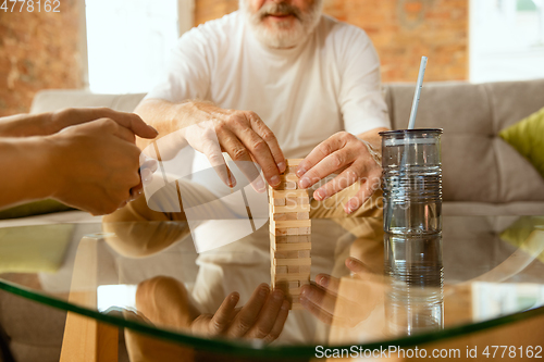 Image of Senior man doing his wooden constructor at home - concept of home studying