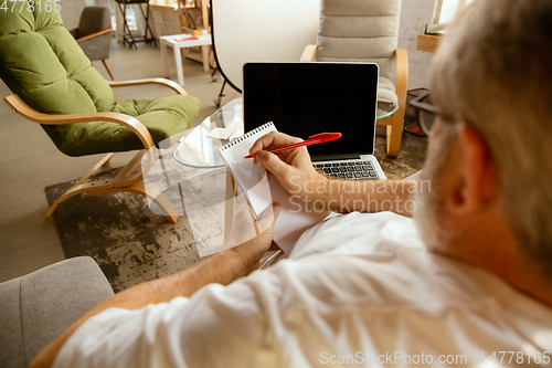 Image of Senior man working with laptop at home - concept of home studying