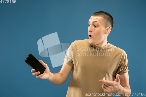 Image of Caucasian young man\'s half-length portrait on blue background