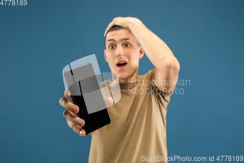 Image of Caucasian young man\'s half-length portrait on blue background