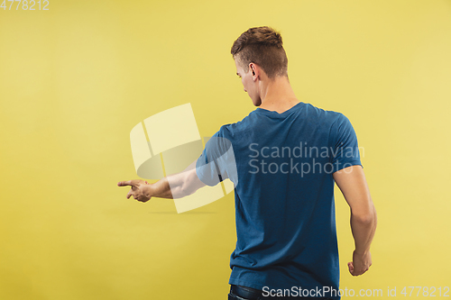 Image of Caucasian young man\'s half-length portrait on yellow background