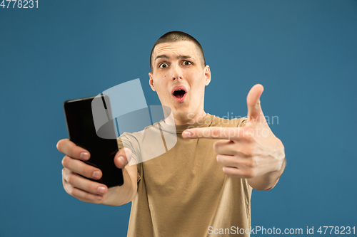 Image of Caucasian young man\'s half-length portrait on blue background