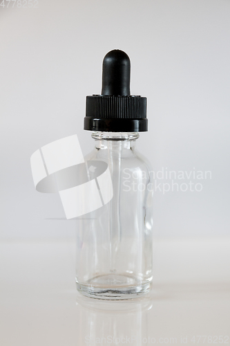 Image of Glass dropper bottle on grey background