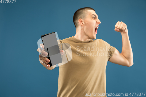 Image of Caucasian young man\'s half-length portrait on blue background