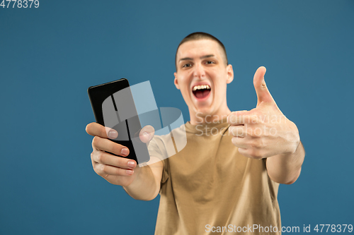 Image of Caucasian young man\'s half-length portrait on blue background