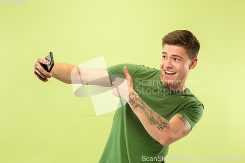Image of Caucasian young man\'s half-length portrait on green background