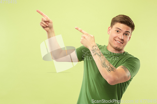 Image of Caucasian young man\'s half-length portrait on green background