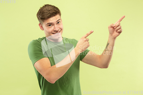 Image of Caucasian young man\'s half-length portrait on green background