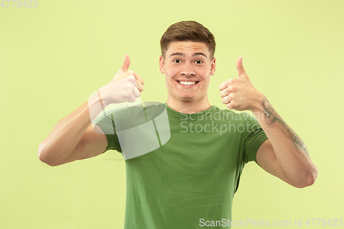 Image of Caucasian young man\'s half-length portrait on green background