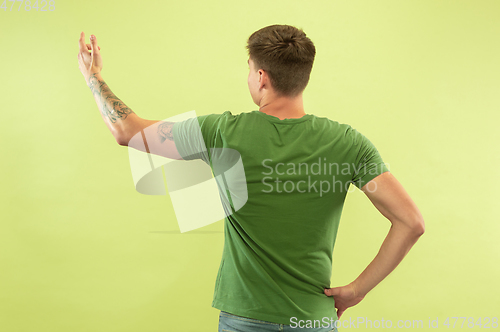 Image of Caucasian young man\'s half-length portrait on green background