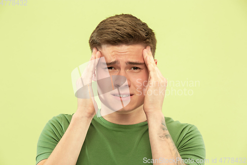 Image of Caucasian young man\'s half-length portrait on green background