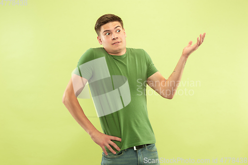 Image of Caucasian young man\'s half-length portrait on green background