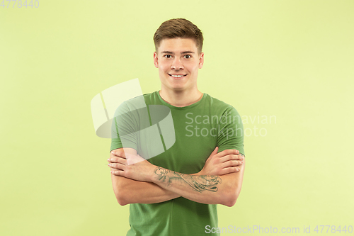 Image of Caucasian young man\'s half-length portrait on green background