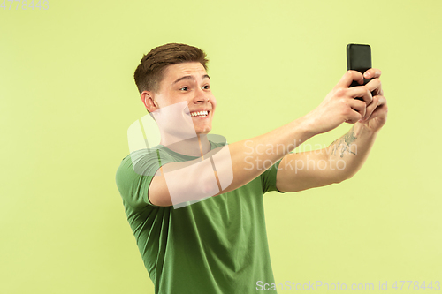 Image of Caucasian young man\'s half-length portrait on green background