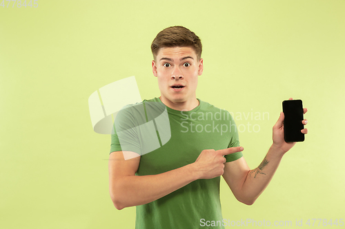 Image of Caucasian young man\'s half-length portrait on green background