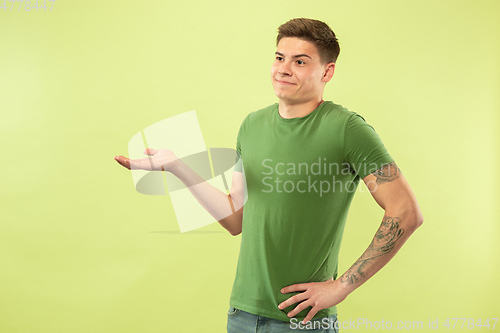 Image of Caucasian young man\'s half-length portrait on green background