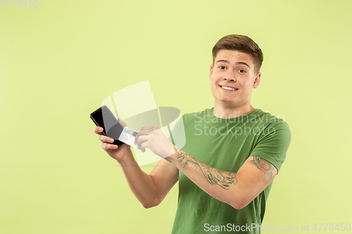 Image of Caucasian young man\'s half-length portrait on green background