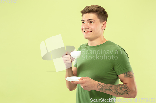 Image of Caucasian young man\'s half-length portrait on green background