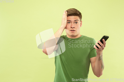 Image of Caucasian young man\'s half-length portrait on green background