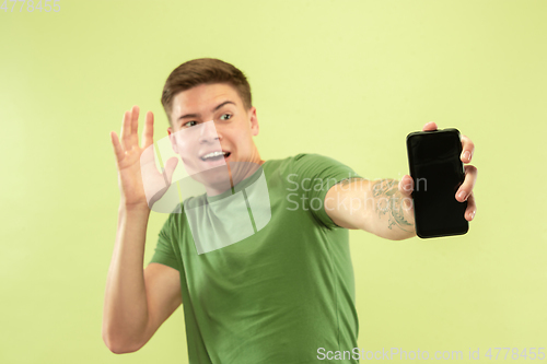 Image of Caucasian young man\'s half-length portrait on green background