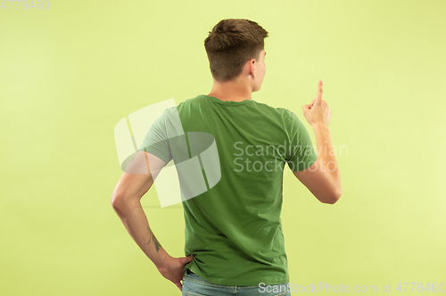 Image of Caucasian young man\'s half-length portrait on green background