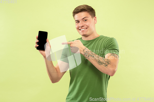 Image of Caucasian young man\'s half-length portrait on green background