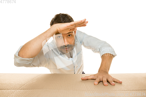 Image of Young man opening the biggest postal package isolated on white