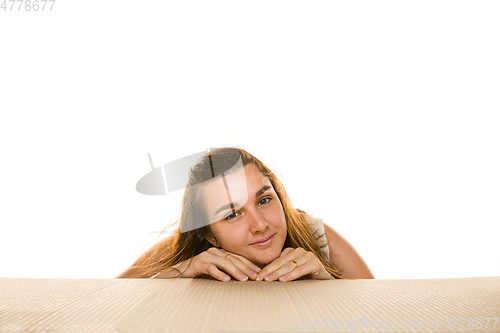 Image of Young woman opening the biggest postal package isolated on white