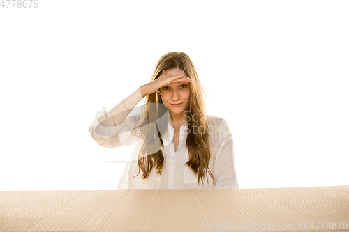 Image of Young woman opening the biggest postal package isolated on white