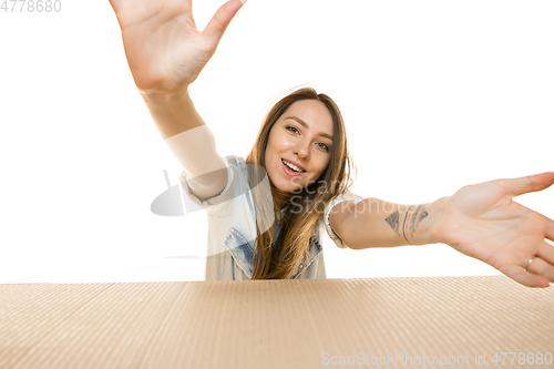 Image of Young woman opening the biggest postal package isolated on white