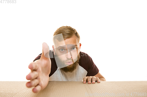 Image of Young man opening the biggest postal package isolated on white