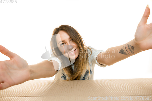 Image of Young woman opening the biggest postal package isolated on white