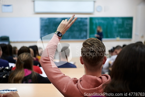 Image of The student raises his hands asking a question in class in college