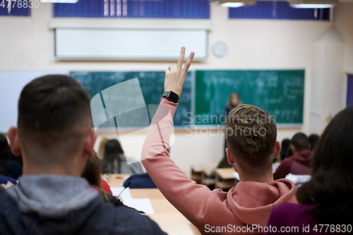 Image of The student raises his hands asking a question in class in college