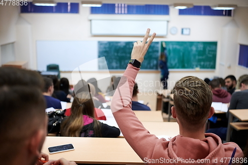 Image of The student raises his hands asking a question in class in college