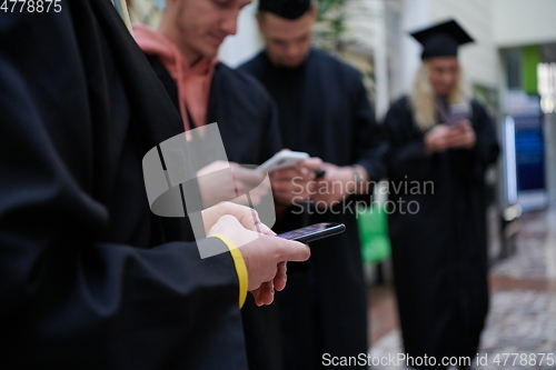 Image of students in mortar boards using smartphone