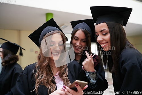 Image of students in mortar boards using smartphone
