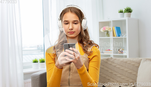 Image of teenage girl in headphones with smartphone at home