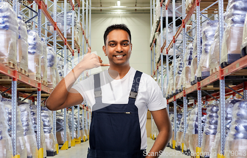 Image of worker making phone call gesture at warehouse